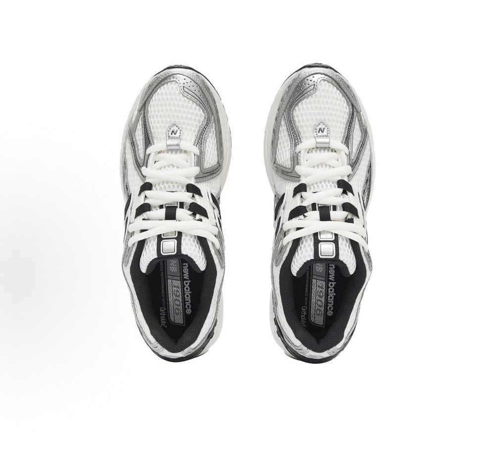 New Balance 1906R pair showing tongues and laces; silver uppers with black logo panels.