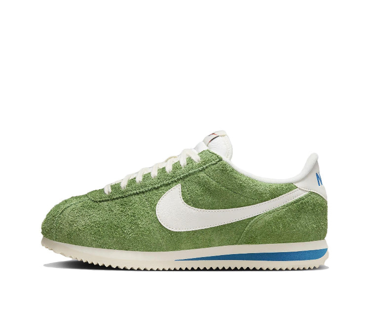 Green suede Nike sneakers with white swoosh, lace-up front, and blue-striped sole