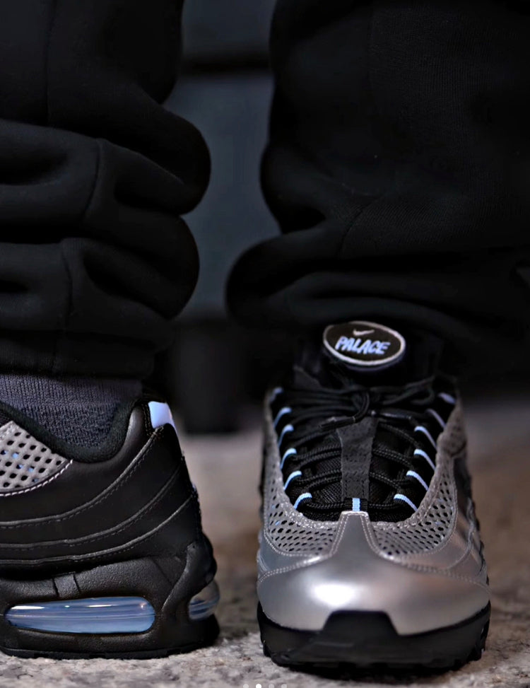 Chunky Air Max sneakers on feet, black uppers with metallic silver toe and blue air