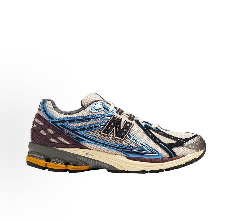 New Balance 1906R side profile with blue, cream, and burgundy mesh panels and laces