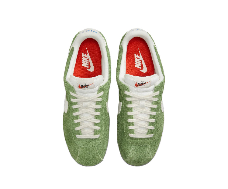 Nike sneakers with green suede uppers, white laces, and red tongue logo