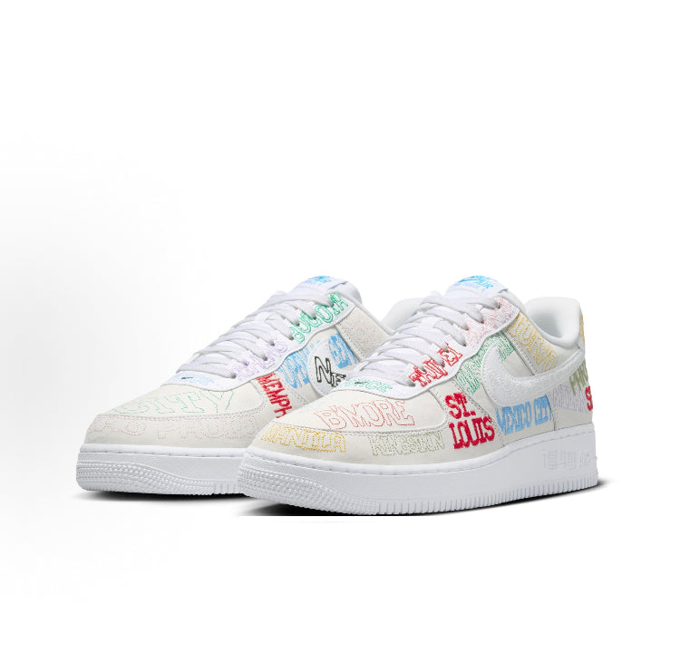 Two low-top sneakers with beige canvas, multicolor text on side panels, white sole