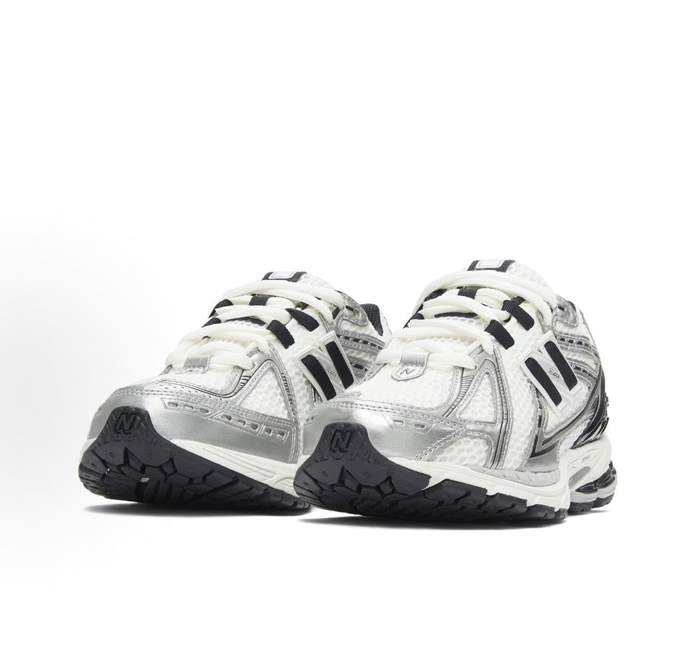 New Balance 1906R lace-up sneakers in silver metallic with black side stripes.
