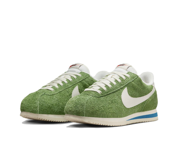 Green suede Nike sneakers with white swoosh, lace-up front, and blue outsole stripe