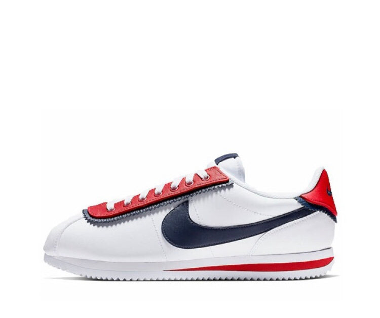 White low-top sneakers with red trim, navy Swoosh, and red heel tab