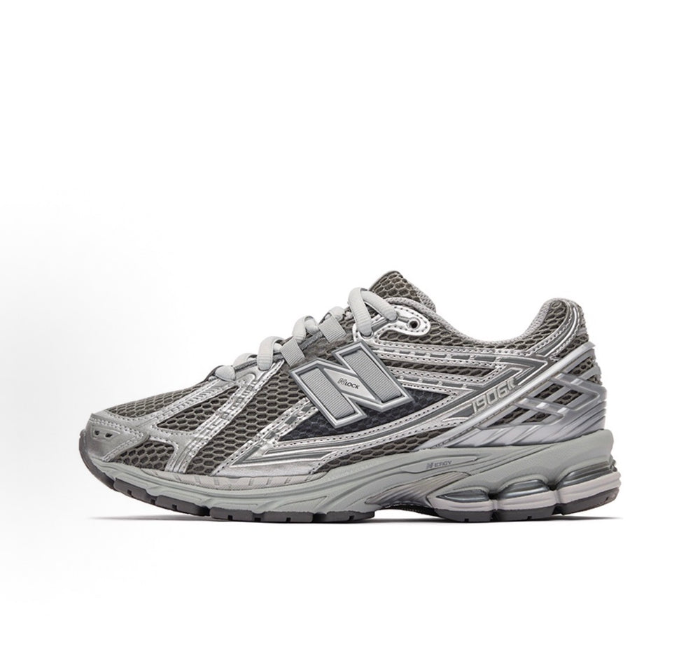 New Balance 1906R sneakers side view, gray mesh with silver overlays and chunky sole.