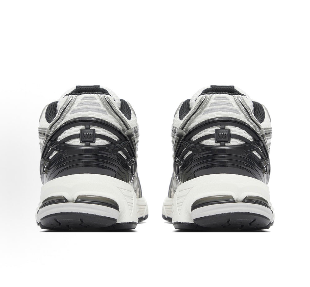 New Balance 1906R heel view sneaker in silver/white with black trim and foam sole.