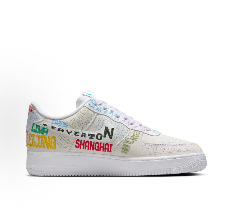 Low-top sneakers with beige upper, multicolor branding text across side, white sole