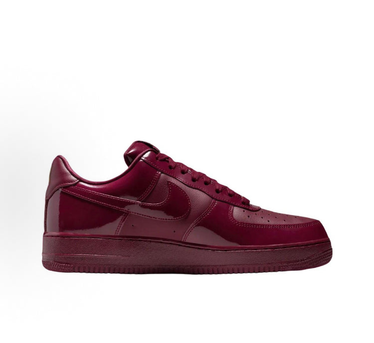 Low-top sneakers in dark maroon with gold Nike swoosh and lace-up eyelets