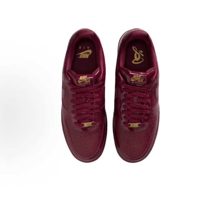 Dark maroon low-top sneakers with gold lace aglets and lace-up front; pair view
