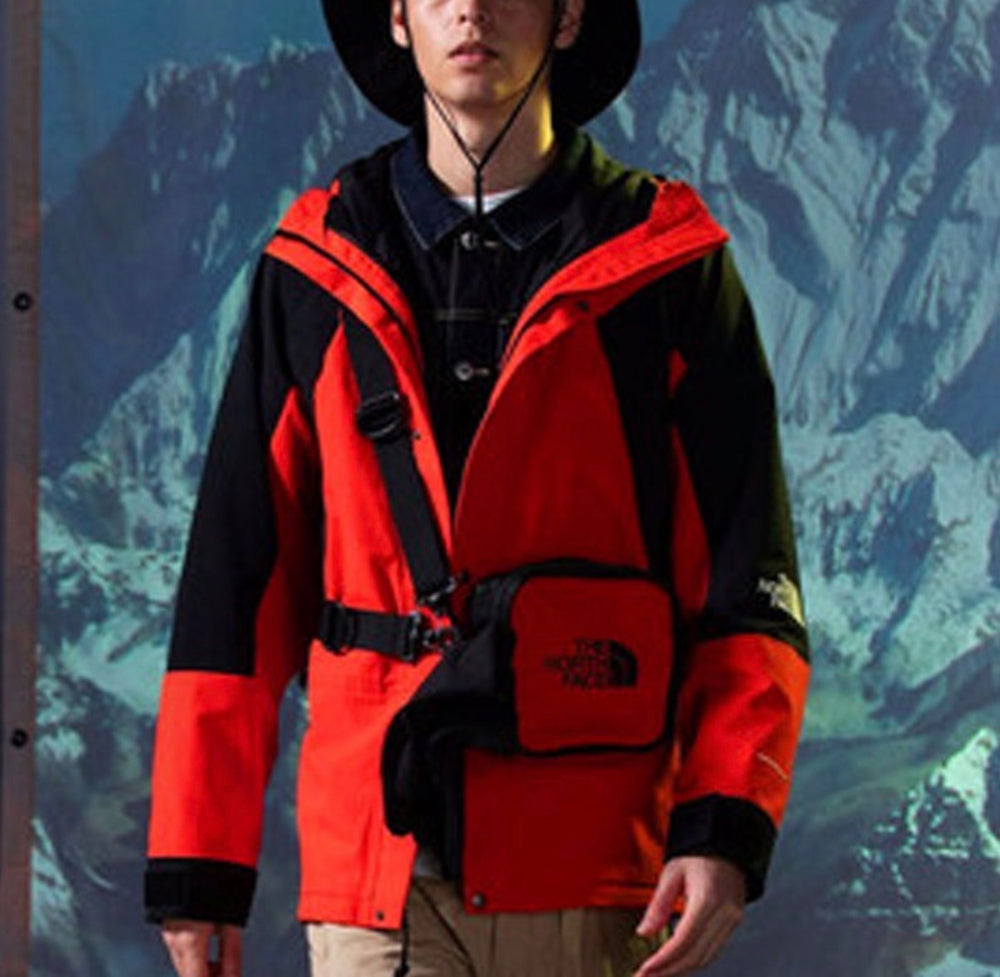 Hooded color-block jacket in bright orange and black, front snap buttons, chest pocket