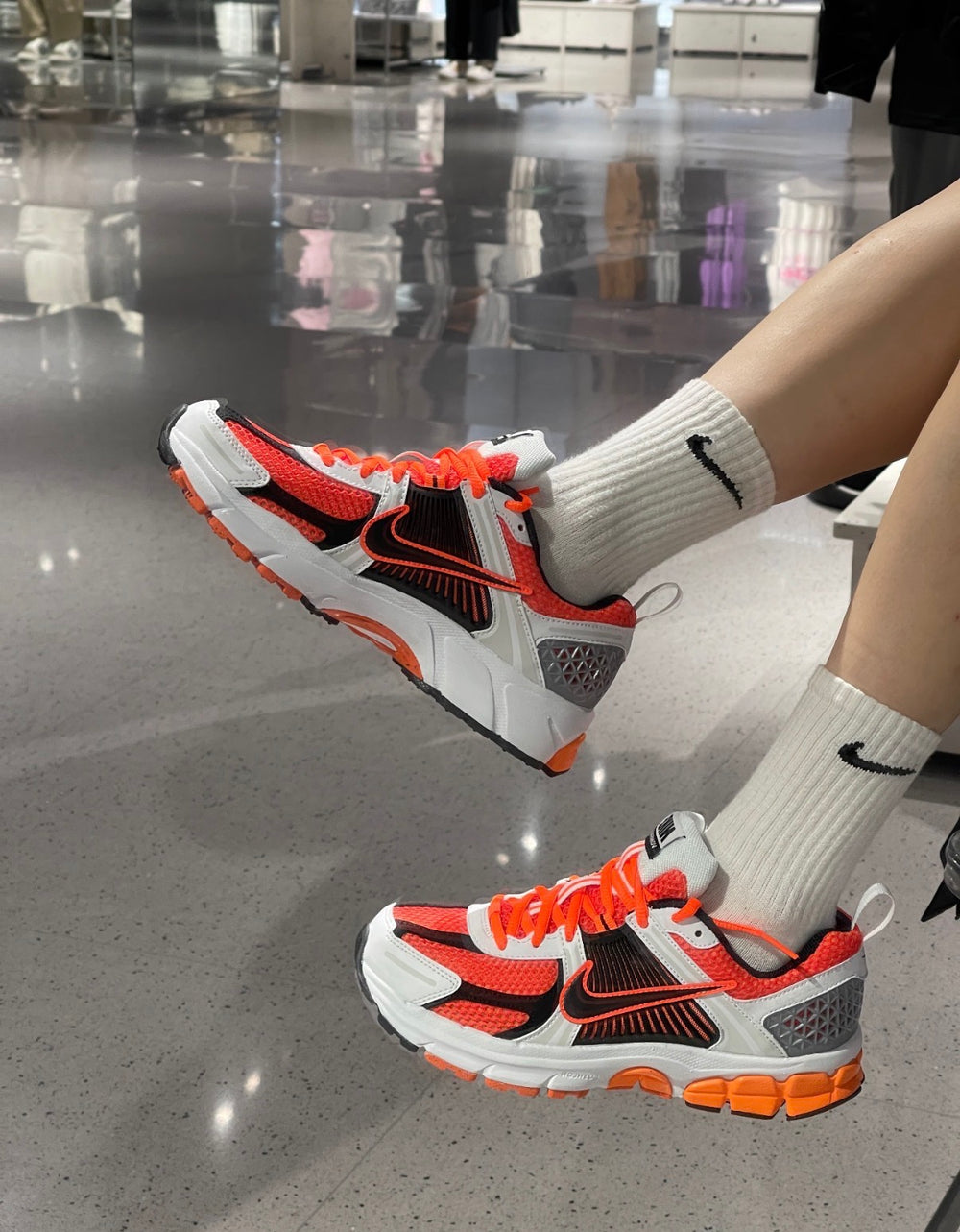 Nike Zoom Vomero 5 SP running shoes, gray with orange laces and black swoosh.