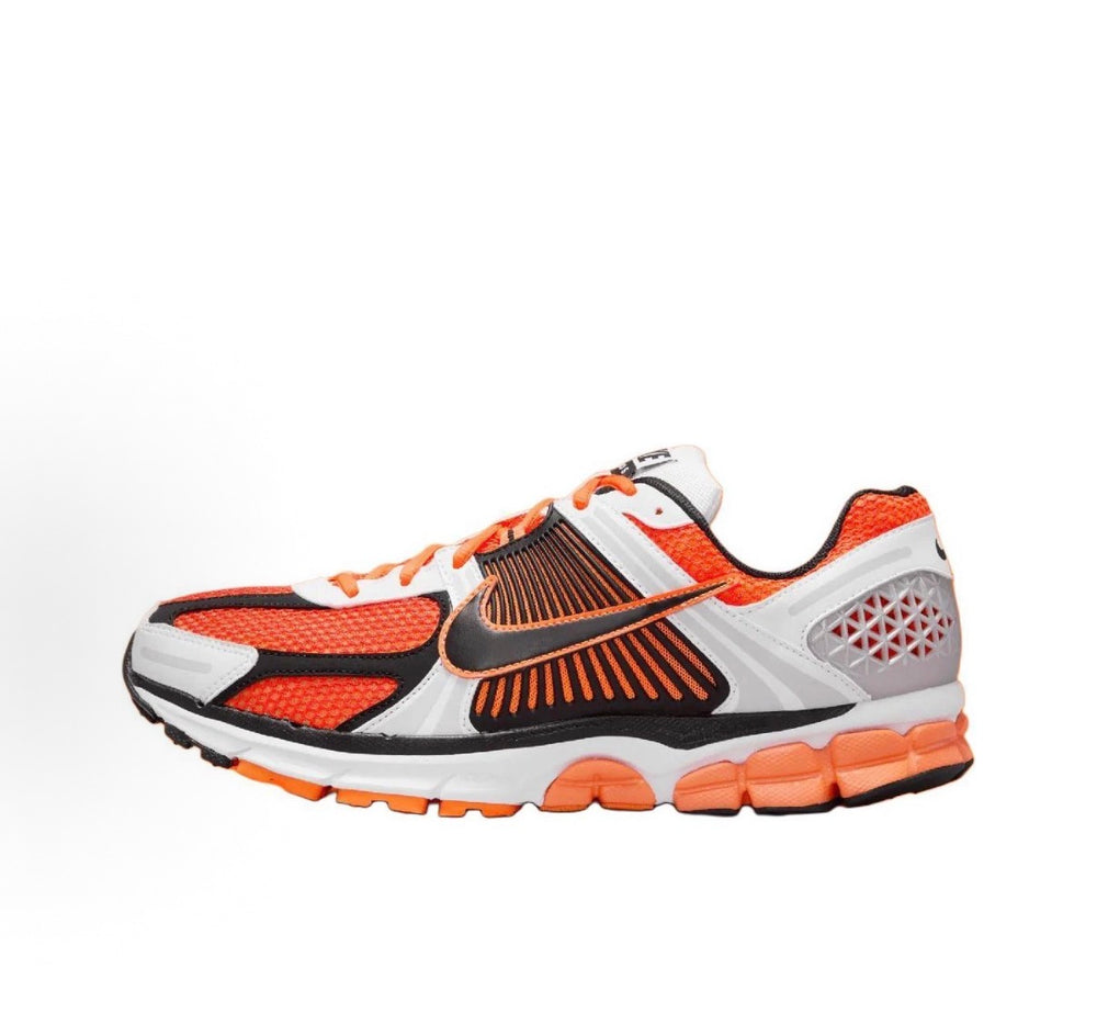 Nike Zoom Vomero 5 SP running shoe, white upper with orange and black accents.