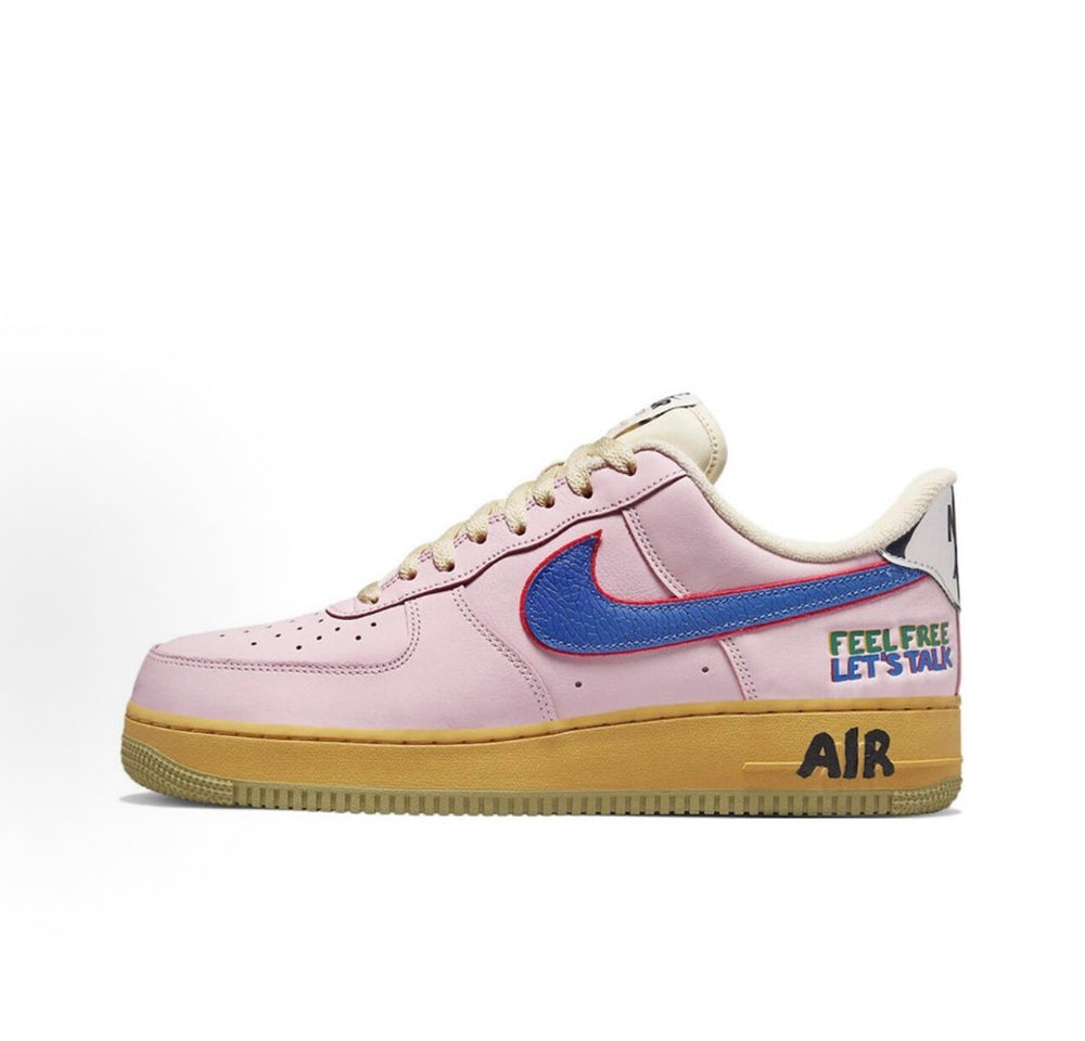 Low-top sneakers with light pink leather, blue swoosh, yellow gum sole, side text graphic