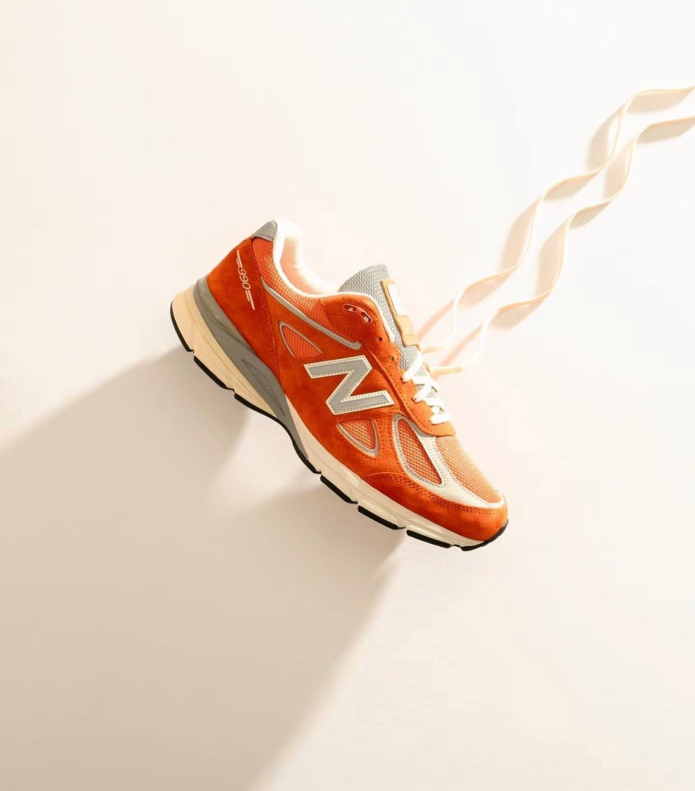 New Balance 990 sneaker with orange upper, white N logo, and gray collar